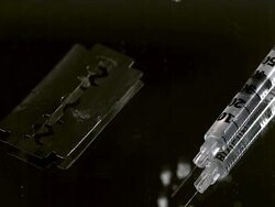CU SLO MO Drug powder falling on razor blade and syringes against black background / Vieux Pont, Normandy, France Stock Footage