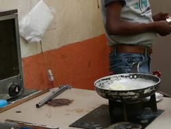A street vendor prepares a packet of Nestle's Maggi noodles over an open kitchen Stock Footage