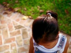 high angle close up PAN PORTRAIT Asian girl looking up at camera + smiling outdoors Stock Footage