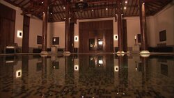 The still water of a hotel swimming pool reflects the columns and lights in the room. Stock Footage