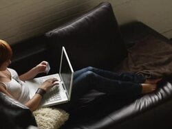 MS HA PAN Young woman using laptop on sofa, holding credit card, Salt Lake City, Utah, USA Stock Footage