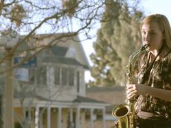 teenager playing brass saxophone practices her instrument in backyard of her home / Redlands, California, USA Stock Footage