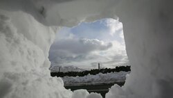 Traffic passing massive snow drifts on the Kirkstone Pass road above Ambleside in the Lake District, UK during the extreme weather event of late March 2013, seen through a snowhole. Stock Footage