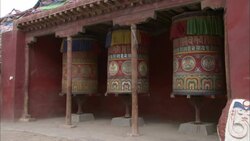 Passers-by spin a prayer wheel in a Tibetan temple. Stock Footage