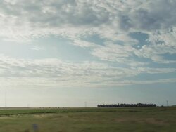 Driving by fields flat farm land and blue sky Stock Footage