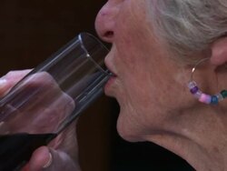 Slow motion handheld close-up shot of an elderly woman drinking wine Stock Footage