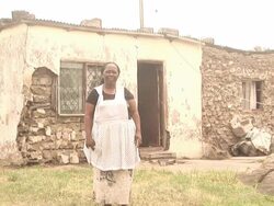African lady stood by house - HD &amp; PAL Stock Footage