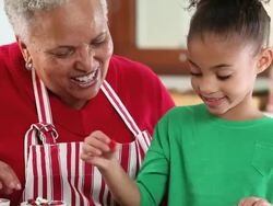 CU TU Grandmother and Granddaughter Decorating Gingerbread Men Cookies in Kitchen / Richmond, Virginia, USA Stock Footage