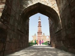 LS Tower Qutub Minar and tourists through archway / Delhi, Punjab, India Stock Footage