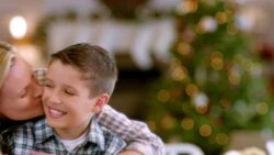 Mother hugs and kisses son, smiles for camera in the kitchen (dolly-shot) Stock Footage