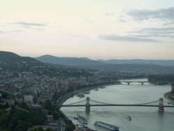 Clear Day-long establishing shot over Danube featuring the Chain Bridge in Budapest, Hungary. From one side of the city to the other then zooms out featuring both sides of the river. Travel destination Stock Footage