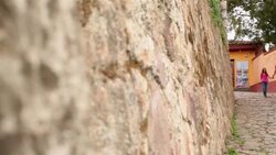 Hispanic brother and sister hold hands walking down third-world street (dolly-shot) Stock Footage