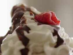 Raspberries fall onto mound of whipped cream and chocolate syrup Stock Footage