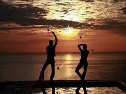 MS Sihouetted couple perform poi dance together in front of fiery sunrise and ocean / Montezuma, Costa Rica Stock Footage