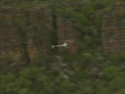 Robinson R22 helicopter flying through gorge, Kakadu National Park, Australia Stock Footage