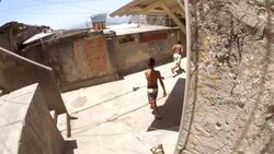 Young Brazilian boys kick soccer ball down narrow alleyways through Rio slums Stock Footage