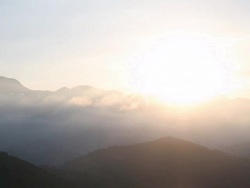 Clouds gather around setting sun, hills Stock Footage