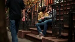 New York couple in love talk and laugh on stoop of brownstone apartment, people cross in foreground (dolly-shot) Stock Footage