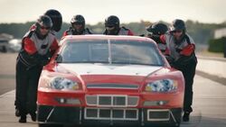 Pit-crew team pushes race-car Stock Footage