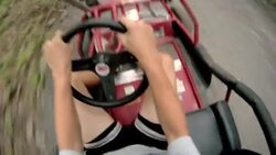 A boy drives a go-kart along a dirt path and stops to unbuckle his seat-belt. Stock Footage