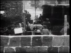 B/W 1961 man holding mirror reflecting sunlight into camera on east side of Berlin Wall Stock Footage
