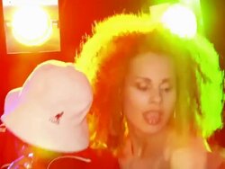 Handheld close-up panning man rapping into microphone, gesturing, two young women dancing behind him Stock Footage