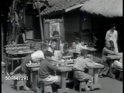 1944: CHINESE EDUCATION: WS Children playing in school yard. Grade school children sitting at table outside, boy in scout uniform (outlawed mainland China 1949) filing airplane of wood. Male teacher explaining use of machine in classroom. Instructional Video