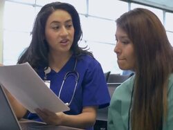 Nursing professor tutoring young Hispanic medical student in college classroom Stock Footage