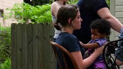 MS PAN Teenage girl holding infant sister in lap during birthday celebration while mom dishes up dessert Stock Footage