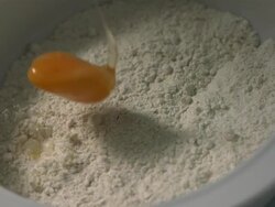 High speed Egg falling in to centre of bowl of flour, high angle Stock Footage