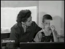 1950: RURAL SCHOOL: Panther Creek class room Registered Nurse checking child's eyesight, boy holding card in front of eye. Eye chart.  Adults passing out milk cartons in class. Children eating hot lunch at desks (25 cents). Instructional Video