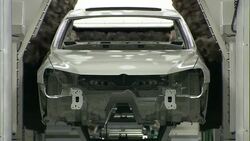 An auto body passes through an automated polishing machine at an automobile factory. Stock Footage