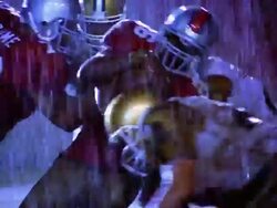OVEREXPOSED football players tackling player carrying ball in rain Stock Footage