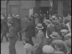 Police officers lead a line of men out of a speakeasy and into paddy wagons. News Clip