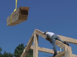 MS ZI Carpenters and crane operator placing rafter beam while framing an energy efficient post / Grass Lake, Michigan, USA      Stock Footage