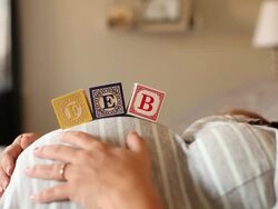 A pregnant women using blocks to spell the month of FEB on her stomach. Stock Footage