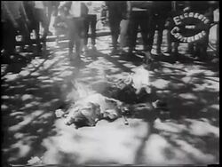 B/W 1967 close up burning Communist flags on ground / people surrounding / pro-Vietnam War demonstration Stock Footage