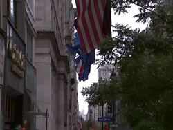 American flags hang above a wet street where pedestrians pass in New York City. Stock Footage