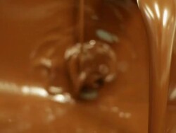 Close up of melted chocolate in large vat being stirred by machine, Belgium Stock Footage