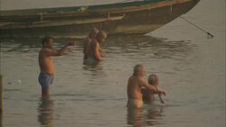 Bathers wash themselves near a docked boat in India. Stock Footage