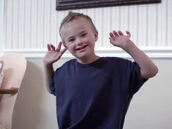 Downs boy sitting on on a table with a tilt and zoom to his face. Stock Footage