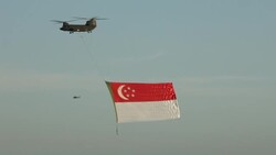 A helicopter carries a giant Singapore flag on National Day. Stock Footage