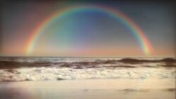 A colorful rainbow crests over ocean tides. Stock Footage