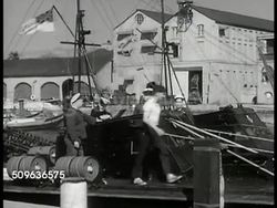 1940: JAMAICA: Docked British Battleship. WS Men working on docked British warship, officers watching deck of ship. TRINIDAD / Tobago: Battleship moored near seawall & dock crane. Sailboat in harbor w/ houses hillside BG. VS British buildings. Instructional Video