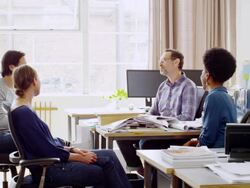 MS laughing coworkers having informal project meeting next to workstations in architects office Stock Footage