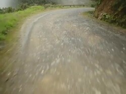 A winding mountain road gives way to a lush canyon with a waterfall. Stock Footage
