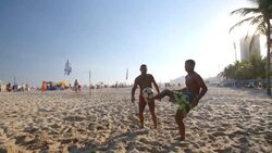 Brazilian player kicks soccer ball up for his partner in heated footvolley match Stock Footage