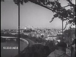1950: ROME, ITALY: CITYSCAPE: Monk walking balcony FG w/ Tiber River below & city of Rome beyond. WS People walking in Piazza della Republica w/ Fontana della Naiadi (Fountain of the Naiads) center. Temple of Vesta (Temple of Sybil) w/ fountain FG. Instructional Video