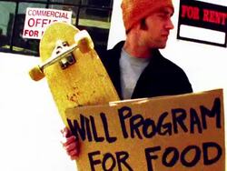 Low angle medium shot tilt up man standing outdoors with skateboard and sign reading 'will program for food' / San Francisco Stock Footage