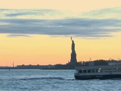 WS View of ferry passing by Statue of Liberty in UNESCO World Heritage Site at dusk  / New York City, New York, USA Stock Footage